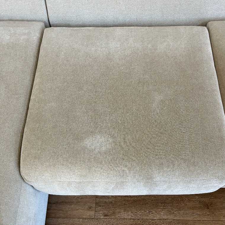 Beige sectional seat cushion before professional upholstery cleaning