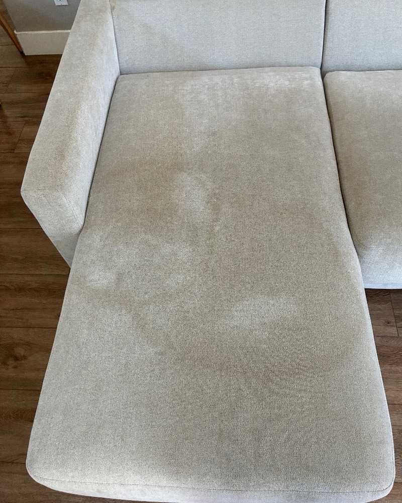 Light gray fabric sectional chaise cushion before professional upholstery cleaning